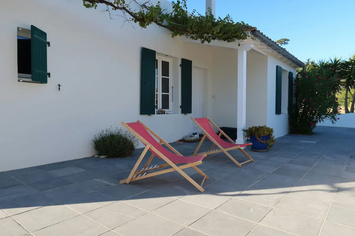 Terrasse dallée de carreaux gris devant une maison blanche