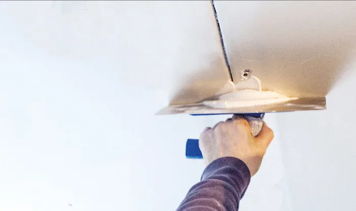 Application de l’enduit placo au couteau sur un plafond